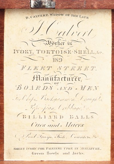 Etikett applicerad på asken till ett engelskt schackspel i svarvat elfenben med "Calvert"-mönster, ca 1826-50 (tryck) av English School