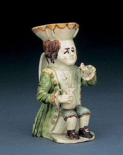 Toper toby-kanna, hans hatt med brun och gul bågad kant, hans inskurna bruna hår i kö och med en vit rosett sittande med en balusterkanna på knäet, ca 1770 av English School