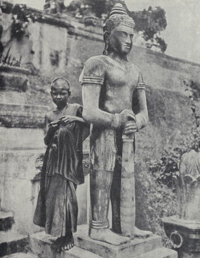 Ung buddhistisk nybörjarmunk bredvid en staty av Buddha, Franska Indokina (s/v foto) av Ewing Galloway