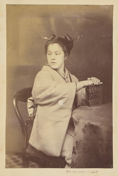 [Sittande japansk kvinna med ett album med cartes-de-visite vid ett bord] av Felice Beato