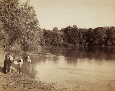 En man i traditionell klädsel med sin häst, framför en sjö i Egypten av Félix Bonfils