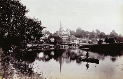 Staden Ross-On-Wye, sett från en flodbank. I förgrunden en man som står på en roddbåt av Francis Frith