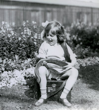 En ung flicka Betty som håller en östlig indigorm när hon sitter på en läderkoffert, London Zoo, 1924 av Frederick William Bond