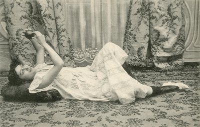 Flicka som ligger på golvet och håller en boll ovanför huvudet (s/v foto) av French Photographer