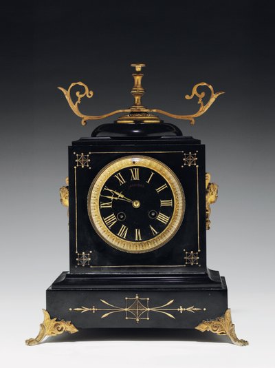 En mantelklocka av svart kompositionssten, med inskuren dekor, med ben, finials och beslag i förgylld mässing, av Jausions of Pau, Frankrike, ca 1876-78 av French School