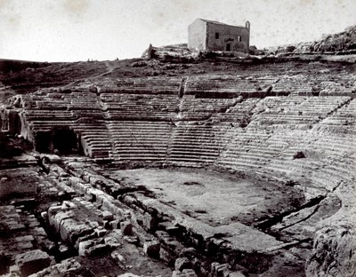 Resterna av den grekiska teatern i Siracusa i Neàpolls monumentala park. I förgrunden den halvcirkelformade orkestern och cavean av Giorgio Sommer