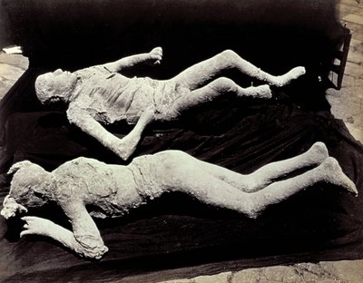 Två avgjutningar av människofigurer från utgrävningarna i Pompeji. Utställningarna placerades på svart tyg för att fotografera dem av Giorgio Sommer