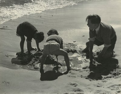 Tre barn leker med sand på stranden. av Godfrey Macdominic