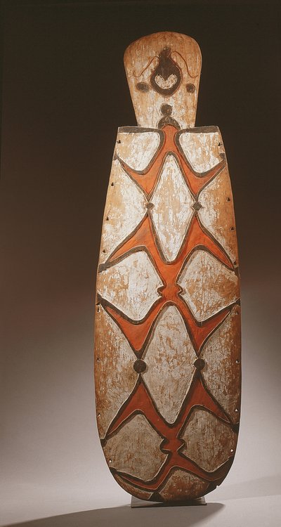 Oval Asmat-sköld, snidad i relief med stiliserade figurer, en mask upptill (trä) av Guinean New