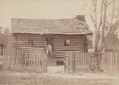 Albumintryck av en kvinna och två barn framför ett timmerhus i Georgia, 1880-talet. av H. S. Clark