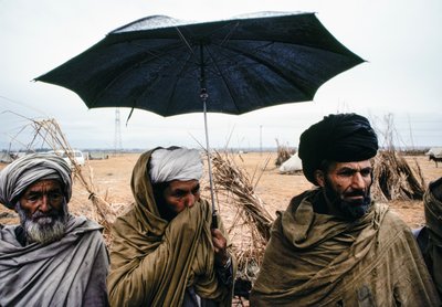 Pakistanska män med paraply och traditionella kläder av James L Stanfield