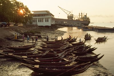Sampans trängs på den leriga stranden vid Nantira Jetty. NANTIRA BRYGGA, RANGOON, BURMA. av James L Stanfield