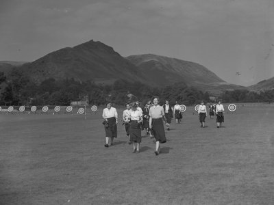 En vy över kvinnliga bågskyttar som möjligen deltar i en tävling, med fjällen i bakgrunden av Joseph Hardman