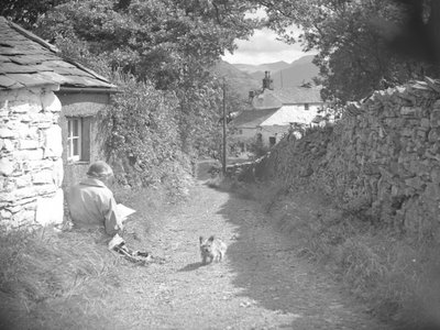 En kvinna satt och läste med en hund i en gränd av Joseph Hardman