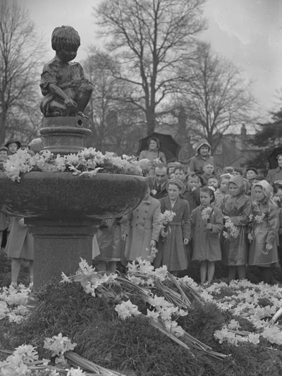 Barn placerar klasar av påskliljor på fontän med staty på toppen av Joseph Hardman