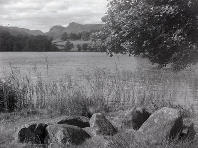 Vy över Loughrigg Tarn, i förgrunden finns några stenar som är nedsänkta i marken av Joseph Hardman