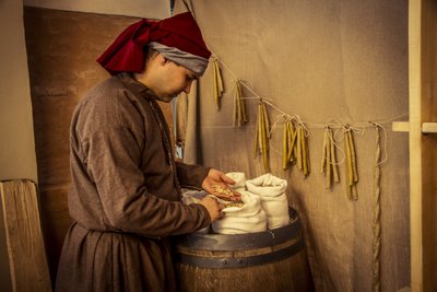 Historisk återskapande: Ljus och säckar med vete, råg och korn i apoteket i Diotaiuti, Imola, Italien, mitten av 1300-talet (foto) av Unbekannt Unbekannt