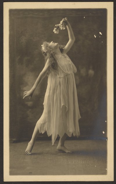 [Dansös med blomma framför en gobeläng] av Louis Fleckenstein