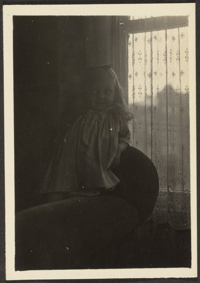 [Liten flicka lutar sig mot stolsrygg] av Louis Fleckenstein