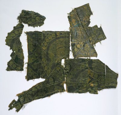 Fragment av en kaftan täckt med ett sidentyg med ett Senmurv-mönster. Moshchevaya Balka begravning M av Medieval Culture of the North Caucasian