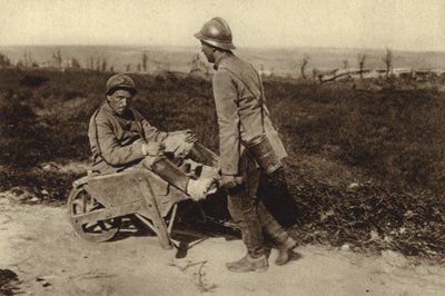 Fången fransk soldat som transporterade sin skadade kamrat i en skottkärra, första världskriget av Photographer German
