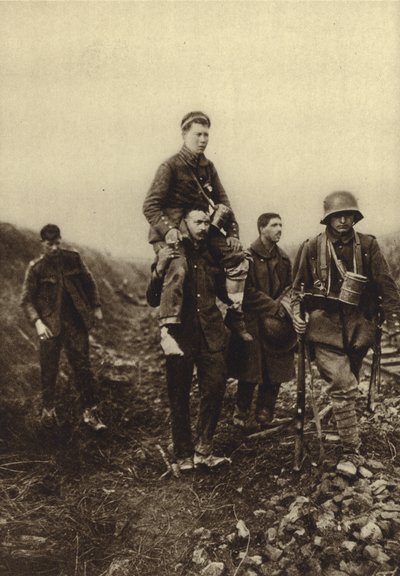 Tysk infanterist med ett bensår som bärs från slagfältet av brittiska fångar, första världskriget av Photographer German