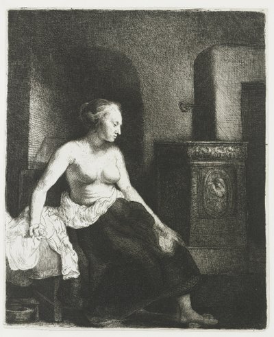 Kvinna som sitter halvklädd bredvid en spis av Rembrandt van Rijn