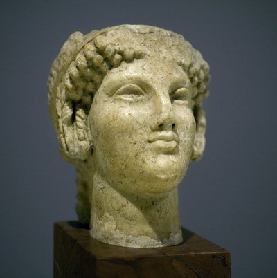Flickhuvud (Kore), skulptur från den romerska hellenistiska perioden (3:e 2:a århundradet efter vår tideräkning), mycket uttrycksfullt ansikte, framträdande kindben i öster, leende, lockigt hår, arkaisk stil av Ionie på 600-talet före vår tideräkning som f av Roman