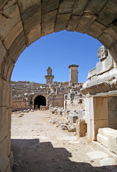 Utsikt genom den välvda ingången till Xanthos-teatern in i orkestergropen, med pelare och harpygrav, Xanthos, Turkiet (foto) av Roman