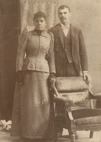 Fotografi av ett afroamerikanskt par som står bakom en stol, ca. 1890. av Schmitz Studio