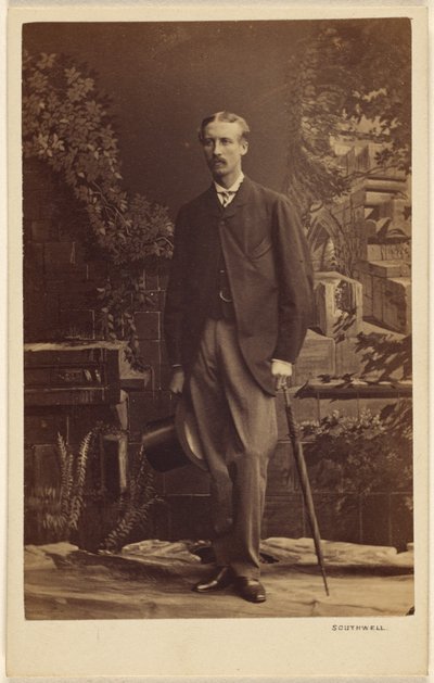 [Oidentifierad man med mustasch, som håller en hög hatt och ett paraply, stående] av Southwell Brothers