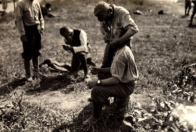 Österrikiska fångar under första världskriget i Bagnaria Arsa, Udine, Italien; i förgrunden rakar en soldat en medsoldat, 1916-04-02 (s/v foto) av Ugo Ojetti
