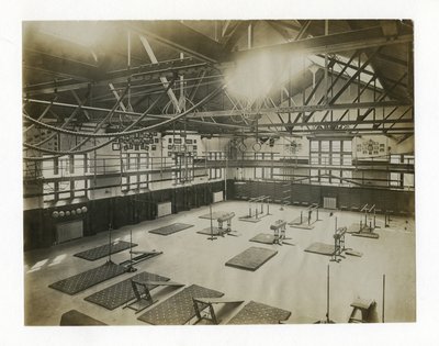 Horisontellt fotografi av interiören i ett stort gym. Utrustning och mattor ligger utspridda på golvet av Unbekannt