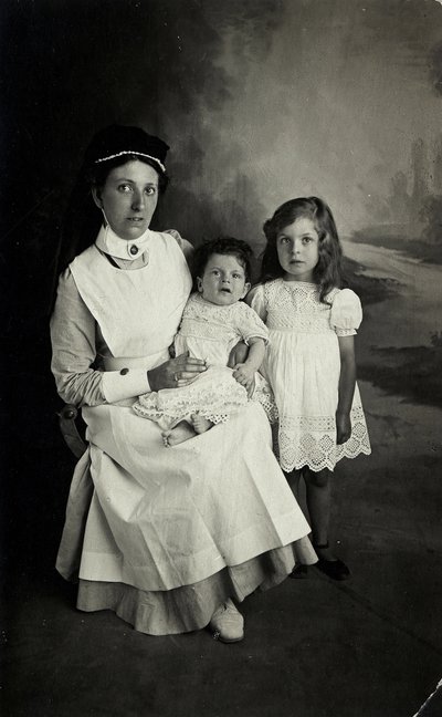 En "sköterska" poserar med barn på 1920-talet. av William M. Timlin
