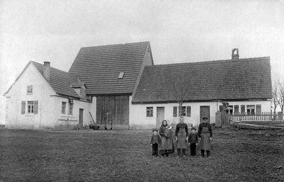 Familj av bönder poserar framför gården. av Unbekannt