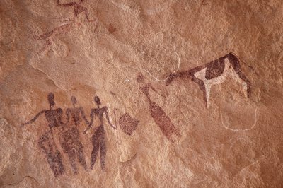 Stenkonst, förhistoria: Stenmålning av en grupp karaktärer och en tvåfärgad ko med stora horn i ett utsmyckat skydd, i Uweinat-massivet, Egypten. (Period från 8000 till 3000 år f.Kr.). Fotografi av Unbekannt
