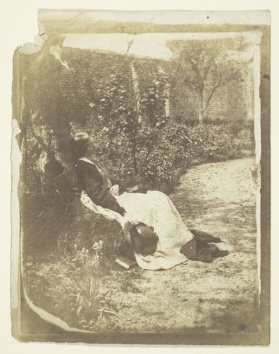 Mrs Craik liggande i trädgården med hatt och bok av Unknown