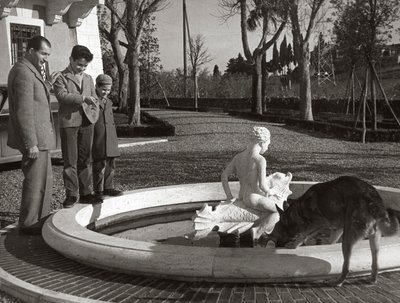 Gino Bartali med två barn och en hund nära en fontän av Unknown photographer
