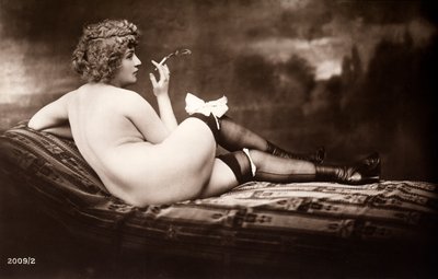 Porträtt av en ung kvinna som poserar naken, med ryggen vänd, medan hon röker en cigarett av Unknown photographer