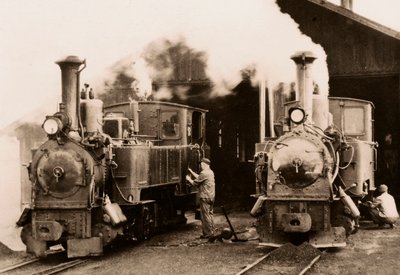 Två ånglok underhålls av två arbetare. av Unknown photographer