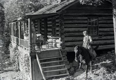 Kvinna, möjligen sjukvårdspersonal, på hästrygg besöker grannar eller familj i... av Volkmar Wentzel