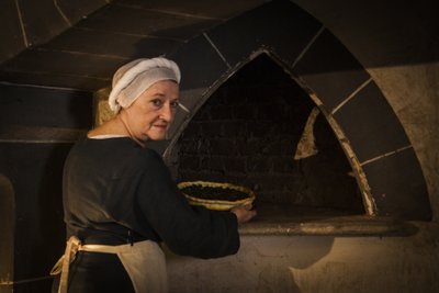Historisk reenactment: Pigan som lägger tårtan i ugnen i köket på slottet av John Ward Dunsmore