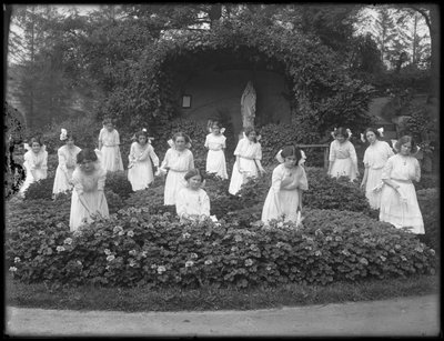 Avgångsklass av flickor från den romersk-katolska föräldralösa asylen i blomsterträdgården, framför Jungfru Marias grotta, 1912 bw foto av William Davis Hassler