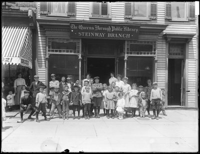 Gruppporträtt av barn framför Steinway-grenen av Queens Borough Public Library, ca 1910 av William Davis Hassler