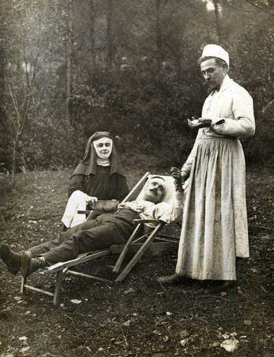 Läkare tar pulsen på en skadad man, assisterad av en nunna, cirka 1900 (s/v foto) av . .