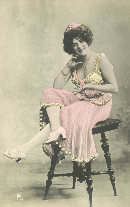 Skådespelerska, med ett fint leende, i rosa klänning som sitter på pall av French Photographer