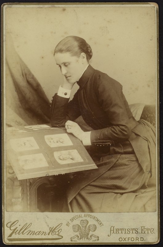 Figur av en kvinna som sitter och inspekterar ett fotoalbum av English Photographer