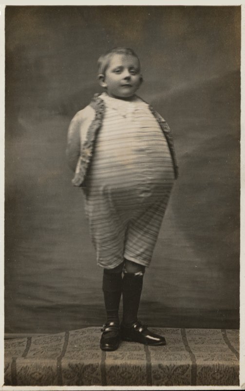 Skolpojke, utklädd för att ha en mycket stor mage (s/v foto) av English Photographer