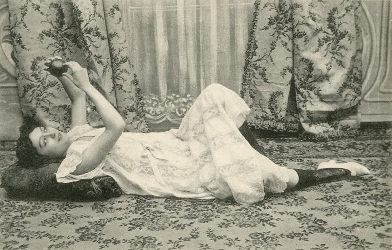 Flicka som ligger på golvet och håller en boll ovanför huvudet (s/v foto) av French Photographer