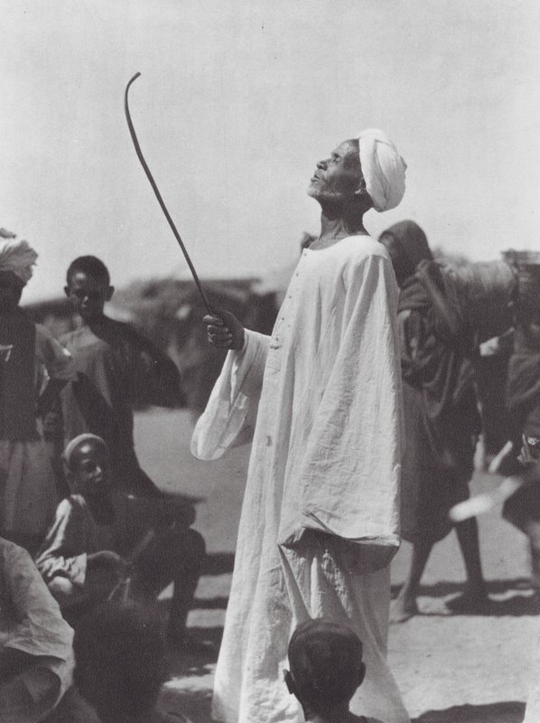 Afrika: Gammal man hånar dansare (svartvitt foto) av Hugo Adolf Bernatzik